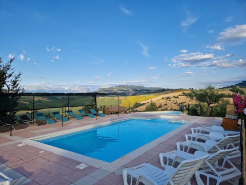 Piscine extérieure, transats et vue panoramique sur les collines à Agricampeggio Tasteria, dans les Marches, Italie.