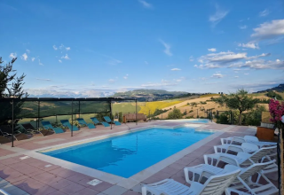 Swimmingpool mit Liegestühlen und herrlichem Ausblick auf die Hügel bei Agricampeggio Tasteria in den Marken.