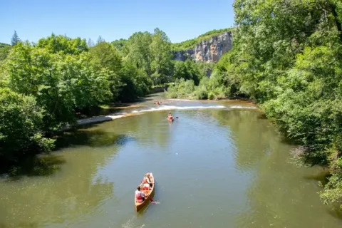 Folk sejler i kano på en flod omgivet af frodig natur nær Montcléra, Occitanie, Frankrig.