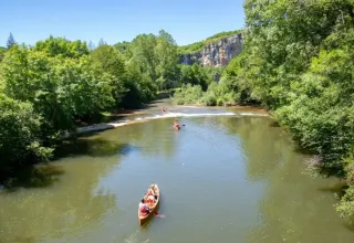 Folk sejler i kano på en flod omgivet af frodig natur nær Montcléra, Occitanie, Frankrig.