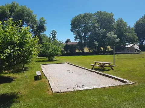Un campo da pétanque, una panchina e un tavolo da picnic nel parco vacanze Les Savonniers in Occitania, Francia.