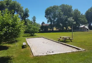 En petanquebane, bænk og picnicbord i grønne omgivelser ved ferieparken Les Savonniers i Occitanie, Frankrig.