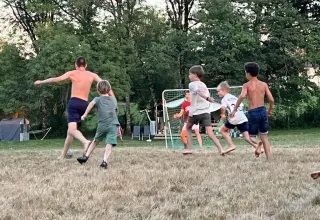 Children and adults play soccer on a grassy field at Les Savonniers holiday park in Occitanie, France.