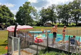 Urlauber entspannen sich am Pool im Ferienpark Les Savonniers in Occitanie, Frankreich, an einem sonnigen Tag.