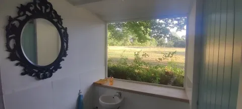 Ein Badezimmer mit großem Fenster und Blick ins Grüne im Les Savonniers Ferienpark in Okzitanien, Frankreich.