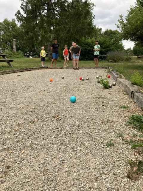 Un grupo de personas juega petanca en una cancha de grava en el parque vacacional Les Savonniers, Occitania, Francia.