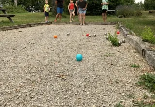 Un grupo de personas juega petanca en una cancha de grava en el parque vacacional Les Savonniers, Occitania, Francia.