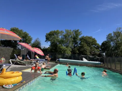 Parque vacacional Les Savonniers en Occitania, Francia, con familias disfrutando de la piscina al aire libre.