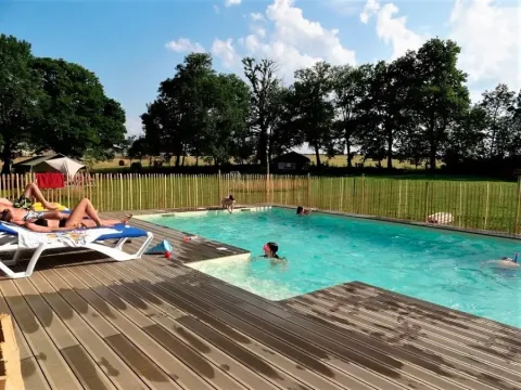 Des vacanciers profitent de la piscine de plein air à Les Savonniers, entourés de verdure en Occitanie, France.