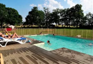 Huéspedes disfrutan en la piscina al aire libre de Les Savonniers, rodeada de naturaleza en Occitanie, Francia.