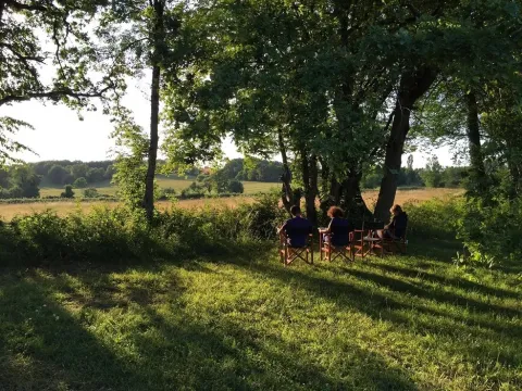 Des gens assis sous les arbres à Les Savonniers, parc de vacances en Occitanie, France, admirant la campagne.