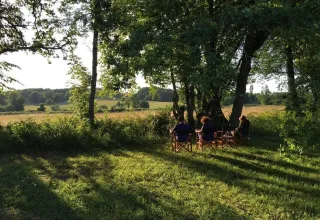 Feriepark Les Savonniers i Occitanie, Frankrig, med folk der sidder i stole under træerne og nyder udsigten.