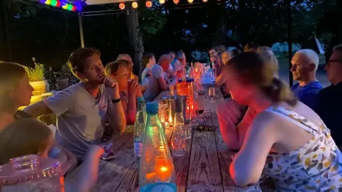 Personas compartiendo una cena iluminada por velas en Les Savonniers, Occitania, Francia, al aire libre.