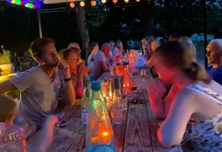 Personas compartiendo una cena iluminada por velas en Les Savonniers, Occitania, Francia, al aire libre.