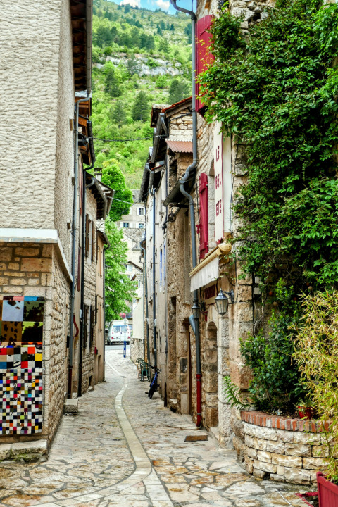Ruelle pavée étroite aux Savonniers, parc de vacances en Occitanie, France, bordée de maisons anciennes et verdure.