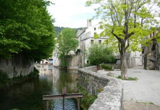 Foto di un fiume con alberi e case antiche al parco vacanze Les Savonniers in Occitania, Francia.