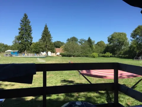 Zicht vanuit een safaritent bij Les Savonniers in Frankrijk, met weides, bomen en blauwe lucht.