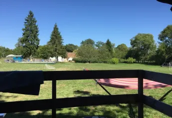 Zicht vanuit een safaritent bij Les Savonniers in Frankrijk, met weides, bomen en blauwe lucht.