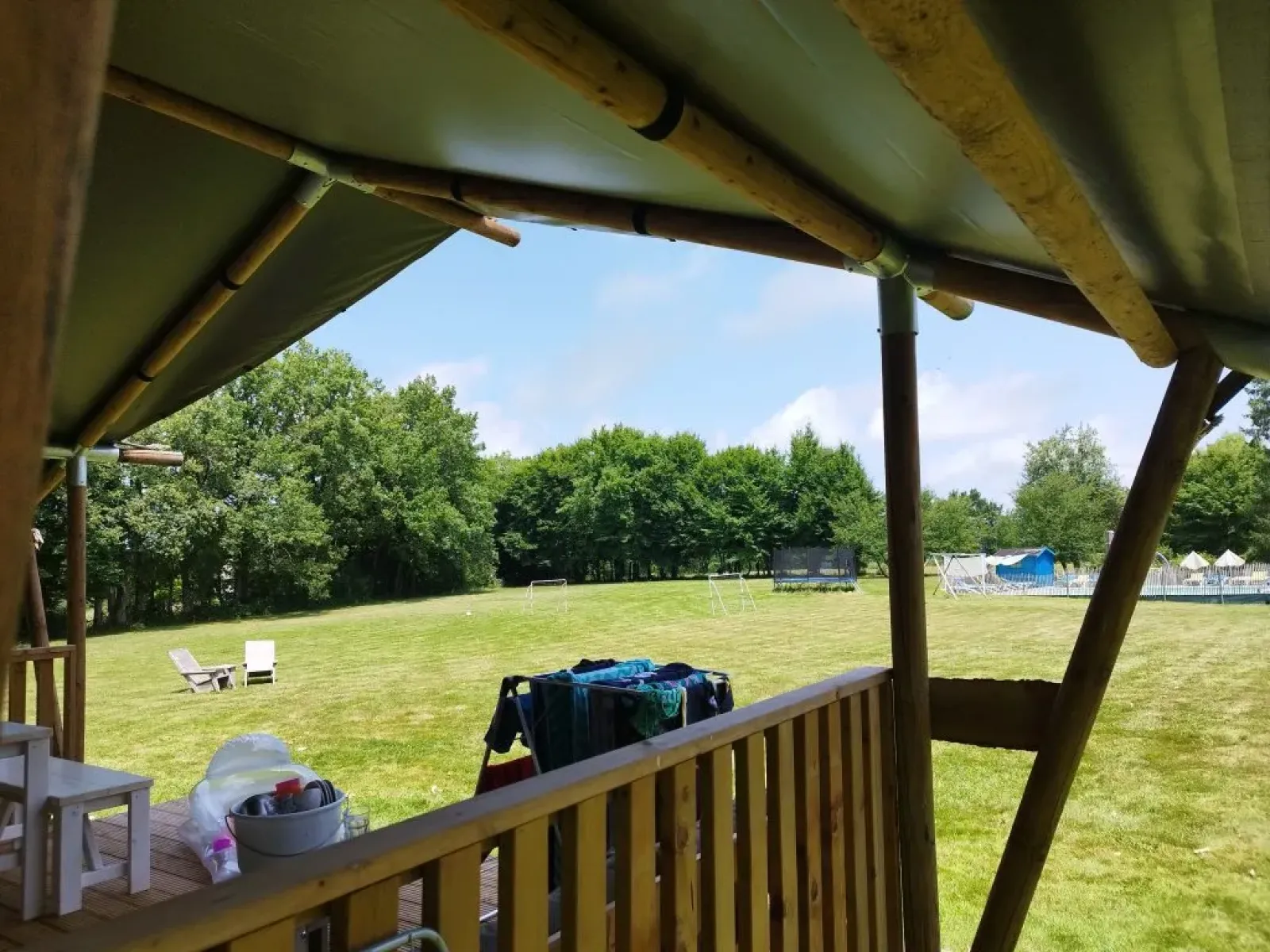 Uitzicht vanaf een safaritentterras bij Les Savonniers in Frankrijk op een groene weide en bomen.