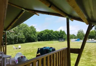 Uitzicht vanop een safaritent bij Les Savonniers in Frankrijk op een grasveld en bomen in de verte.