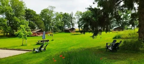Groene kampeerweide met safaritenten, bomen en buitenstoelen bij Les Savonniers in Frankrijk.