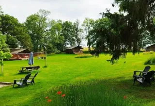 Groene kampeerweide met safaritenten, bomen en buitenstoelen bij Les Savonniers in Frankrijk.