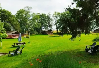 Groene kampeerweide met safaritenten, bomen en buitenstoelen bij Les Savonniers in Frankrijk.