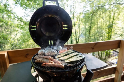 Barbecue avec saucisses et légumes sur le balcon d'une tente safari au Camping La Bretonniere en France.