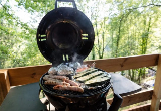 Barbacoa asando salchichas y verduras en el balcón de una tienda safari en Camping La Bretonniere, Francia.