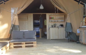 Cozy safari tent interior with seating, kitchenette, and natural ambiance at Camping La Bretonniere, France.