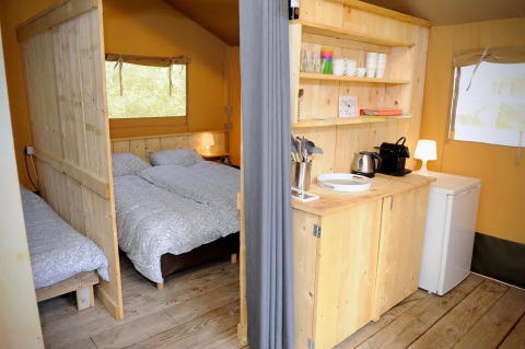 Safari-Zelt mit Schlafbereich, Küchenzeile und Holzmöbeln auf Camping La Bretonniere in Frankreich.