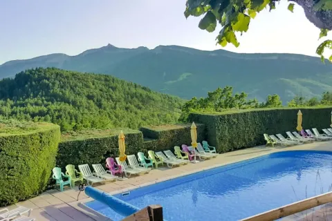 Zwembad en ligstoelen bij Domaine Les 2 Soleils, met uitzicht op bergen in de Provence-Alpes-Côte d’Azur.
