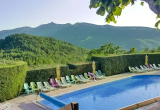 Zwembad en ligstoelen bij Domaine Les 2 Soleils, met uitzicht op bergen in de Provence-Alpes-Côte d’Azur.