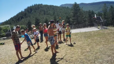 Kinderen en volwassenen spelen buiten bij Domaine Les 2 Soleils in Provence-Alpes-Côte d’Azur, Frankrijk, omgeven door bergen.