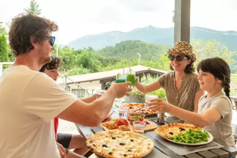 Gezin geniet van pizza en drankjes buiten met bergzicht bij Domaine Les 2 Soleils in de Provence.