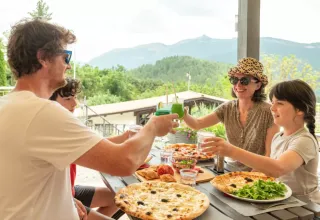 Gezin geniet van pizza en drankjes buiten met bergzicht bij Domaine Les 2 Soleils in de Provence.