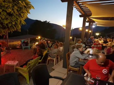 Avondsfeer bij Domaine Les 2 Soleils: gasten buiten, sfeerverlichting en uitzicht op bergen in de Provence.