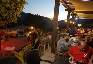 Avondsfeer bij Domaine Les 2 Soleils: gasten buiten, sfeerverlichting en uitzicht op bergen in de Provence.