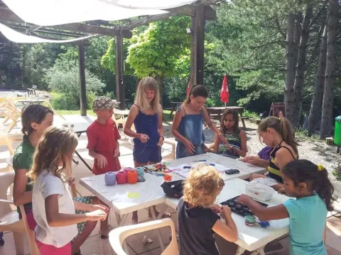 Kinderen en volwassenen knutselen samen buiten aan een tafel bij Domaine Les 2 Soleils in Zuid-Frankrijk.