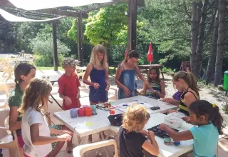 Kinderen en volwassenen knutselen samen buiten aan een tafel bij Domaine Les 2 Soleils in Zuid-Frankrijk.