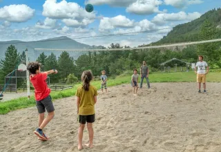 Kinderen en volwassenen spelen volleybal op een zandveld bij Domaine Les 2 Soleils in Provence-Alpes-Côte d’Azur.