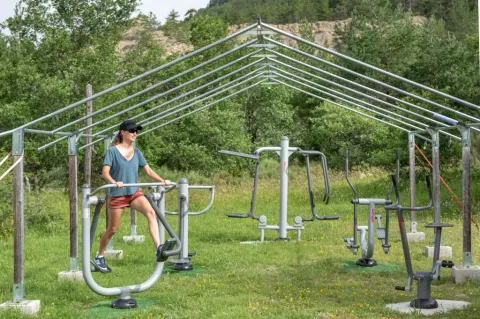 Vrouw traint op buitensportschoolapparatuur bij Domaine Les 2 Soleils vakantiepark in de Provence, Frankrijk.