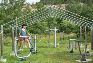 Vrouw traint op buitensportschoolapparatuur bij Domaine Les 2 Soleils vakantiepark in de Provence, Frankrijk.