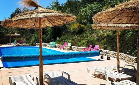 Buitenzwembad met stroparasols en ligstoelen bij Domaine Les 2 Soleils in Provence-Alpes-Côte d’Azur, Frankrijk.