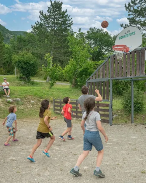 Kinderen en volwassenen spelen basketbal buiten bij Domaine Les 2 Soleils, vakantiepark in Zuid-Frankrijk.