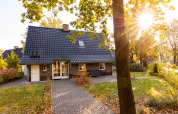 Lodge Wellness XXL en Hof van Salland, Países Bajos, rodeada de jardín y árboles con luz solar cálida.