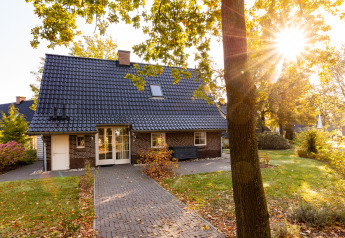 Lodge Wellness XXL en Hof van Salland, Países Bajos, rodeada de jardín y árboles con luz solar cálida.