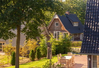 Vista exterior de Wellness Lodge XXL en Hof van Salland, Países Bajos, con jardín y muebles de terraza.