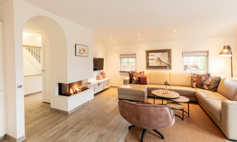 Moderne woonkamer in Wellness Lodge XXL bij Hof van Salland, Nederland, met haard en grote zetel.