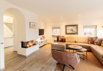 Sala moderna en Wellness Lodge XXL, Hof van Salland, Países Bajos, con chimenea y sofá en forma de L.